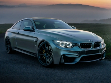 夕焼け空をバックにアスファルトに駐車されたシルバーのスポーツカー