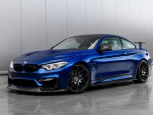 グレーの壁で、光沢のある床に駐車された、濃い青色のスポーツカー